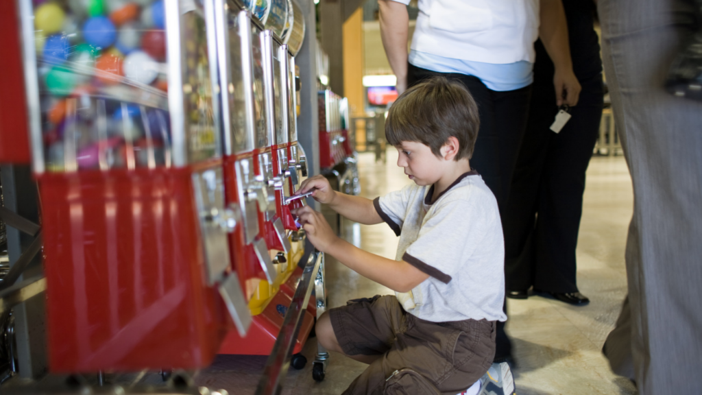 boy putting quarters in a gumball machine